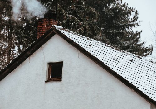 Smoke coming out of a chimney on the snow-covered rood of a house